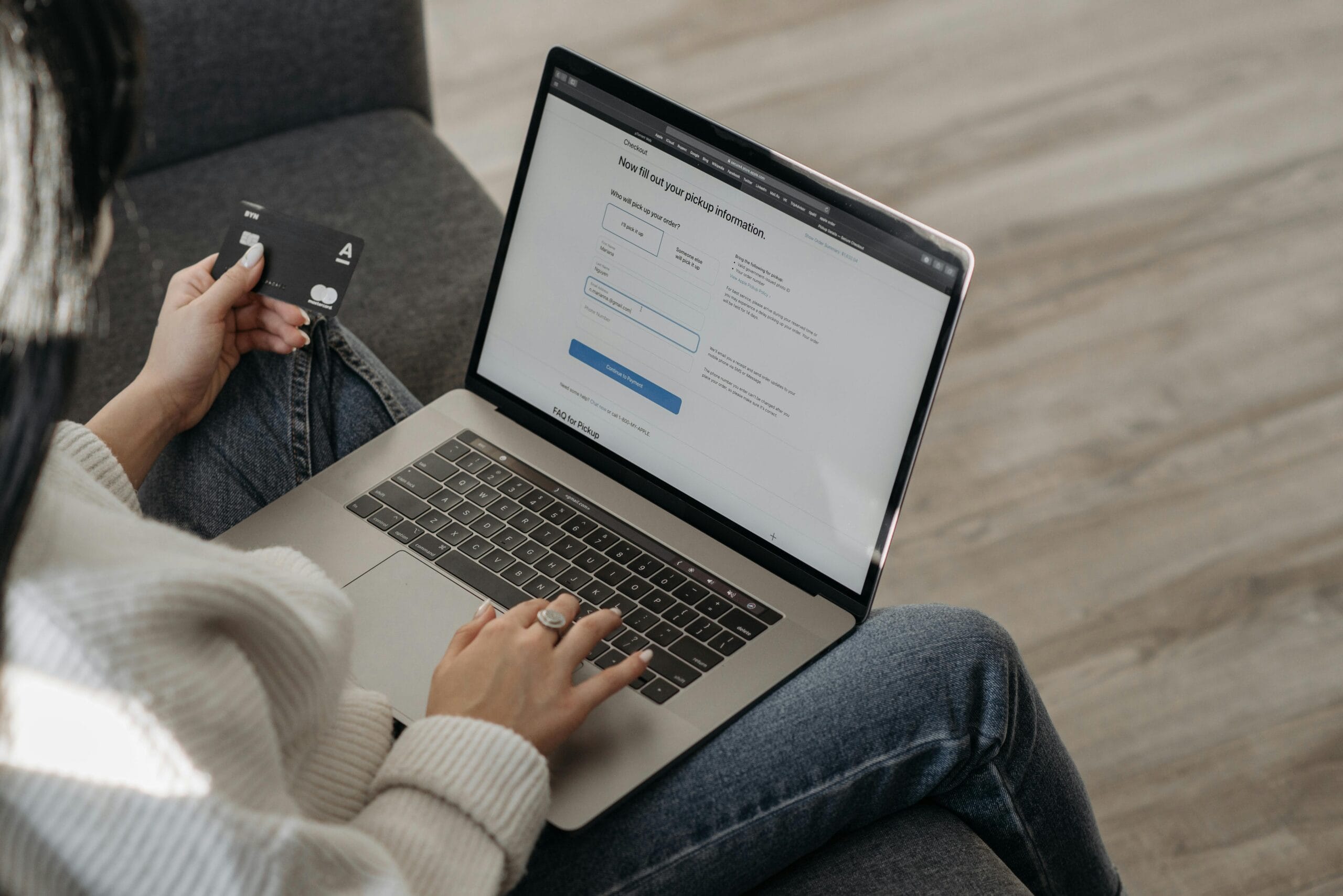 Kobieta trzymająca kartę kredytową, wpisująca dane do laptopa w celu dokonania zakupu. Zdjęcie akcentuje końcowy etap ścieżki zakupowej, w którym jasne i wiarygodne teksty sprzedażowe ułatwiają proces płatności i eliminują wątpliwości.