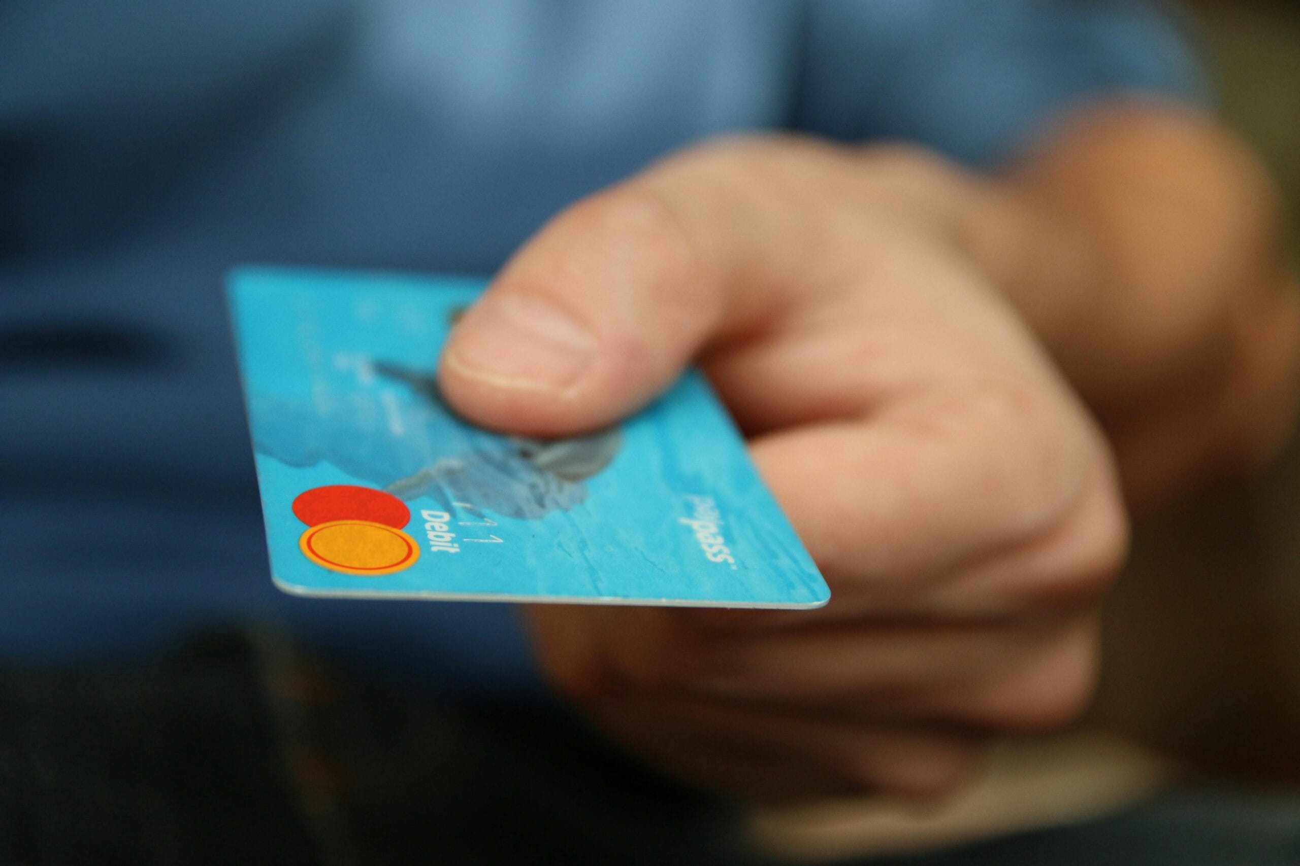 Zbliżenie na dłoń trzymającą kartę debetową Mastercard, gotową do dokonania płatności. Ilustruje to kluczowy moment w copywritingu sprzedażowym – efektywne call to action (CTA), które prowadzi do finalizacji zakupu i konwersji.